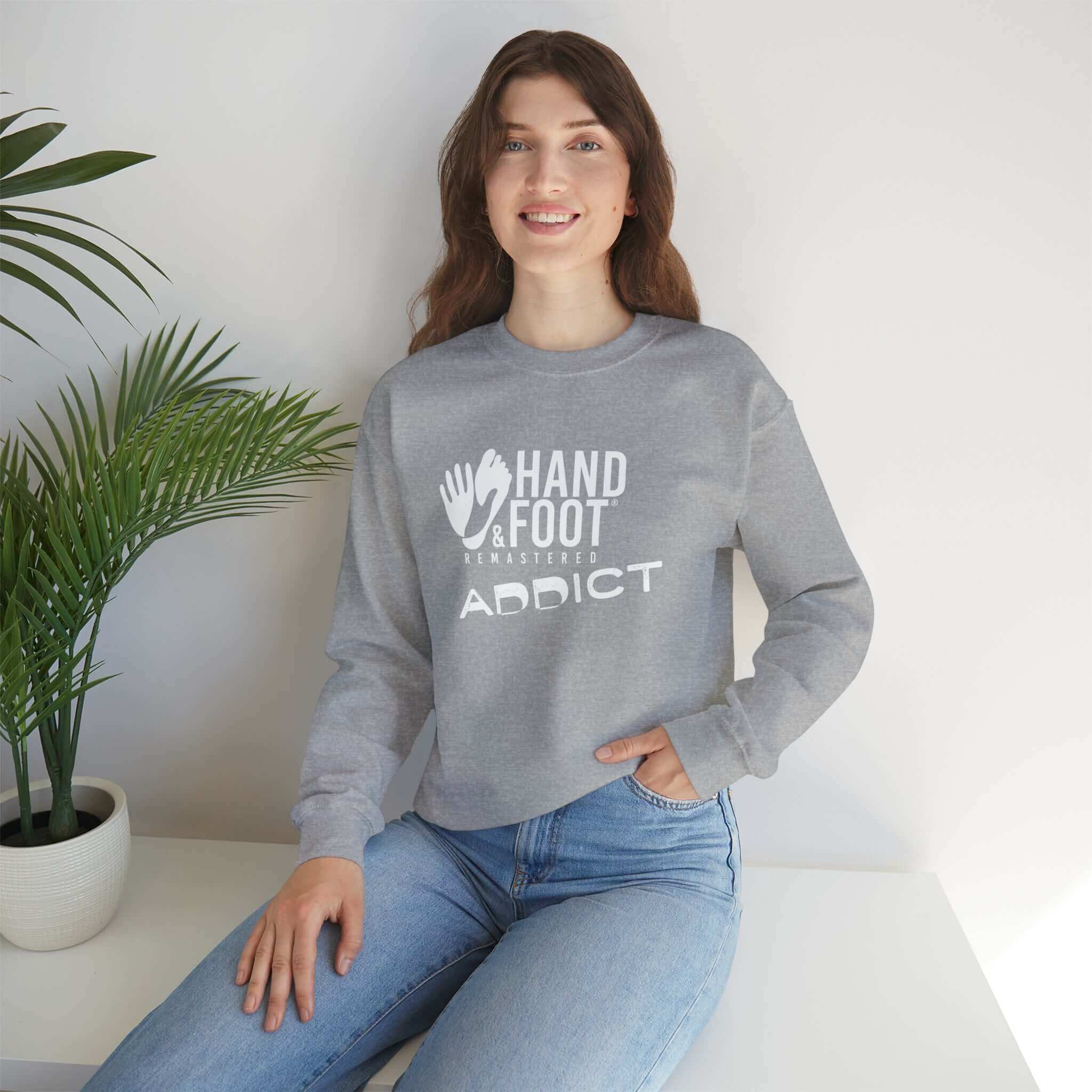 Unisex crewneck sweatshirt with 'Hand & Foot Addict' design, worn by model, featuring cozy, sustainable fashion in a casual setting.