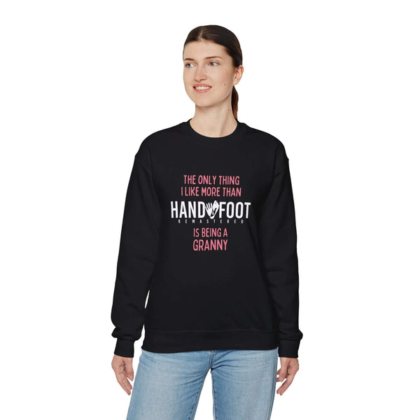 Woman wearing a black "Being a Granny" unisex crewneck sweatshirt, featuring a fun hand and foot print design.