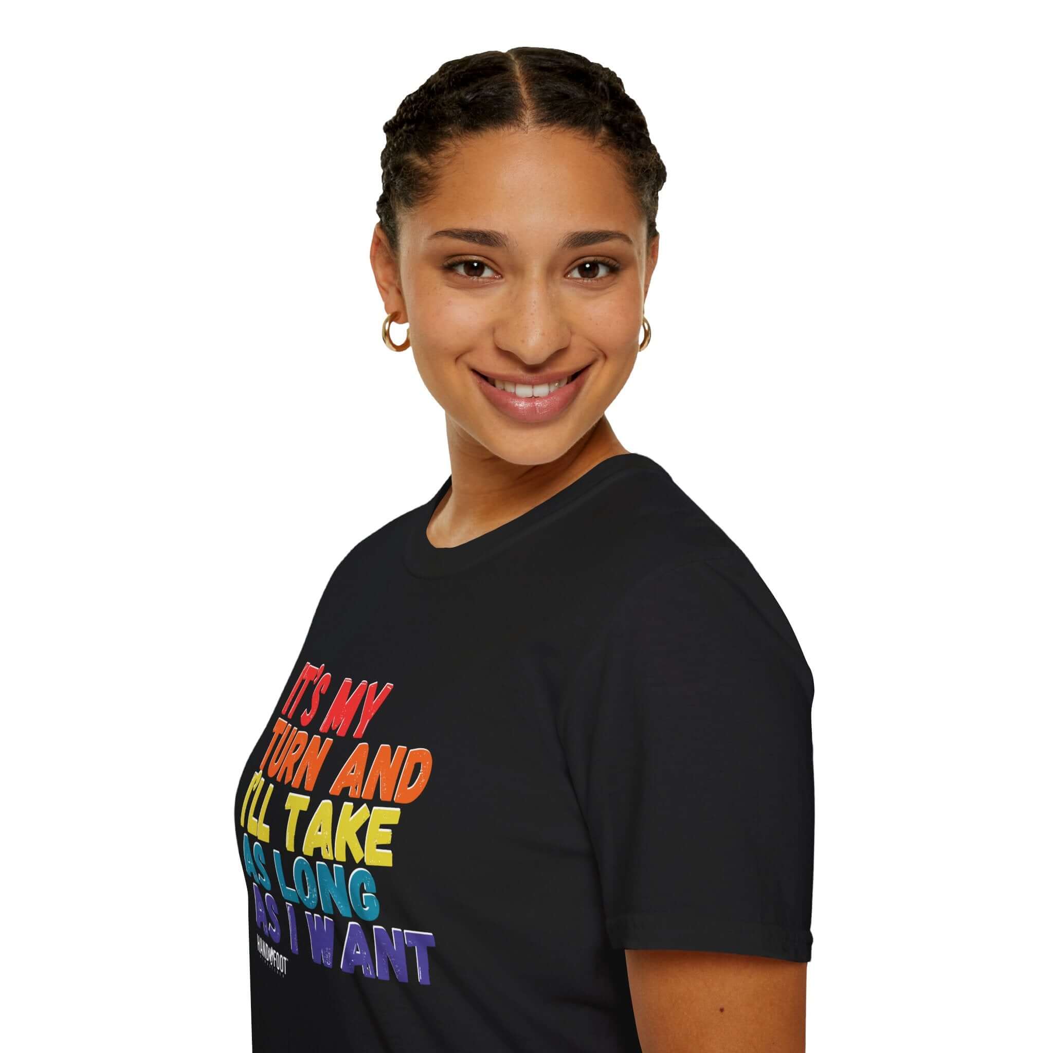 Smiling person wearing 'It's My Turn' Softstyle T-Shirt in black, featuring colorful print text.