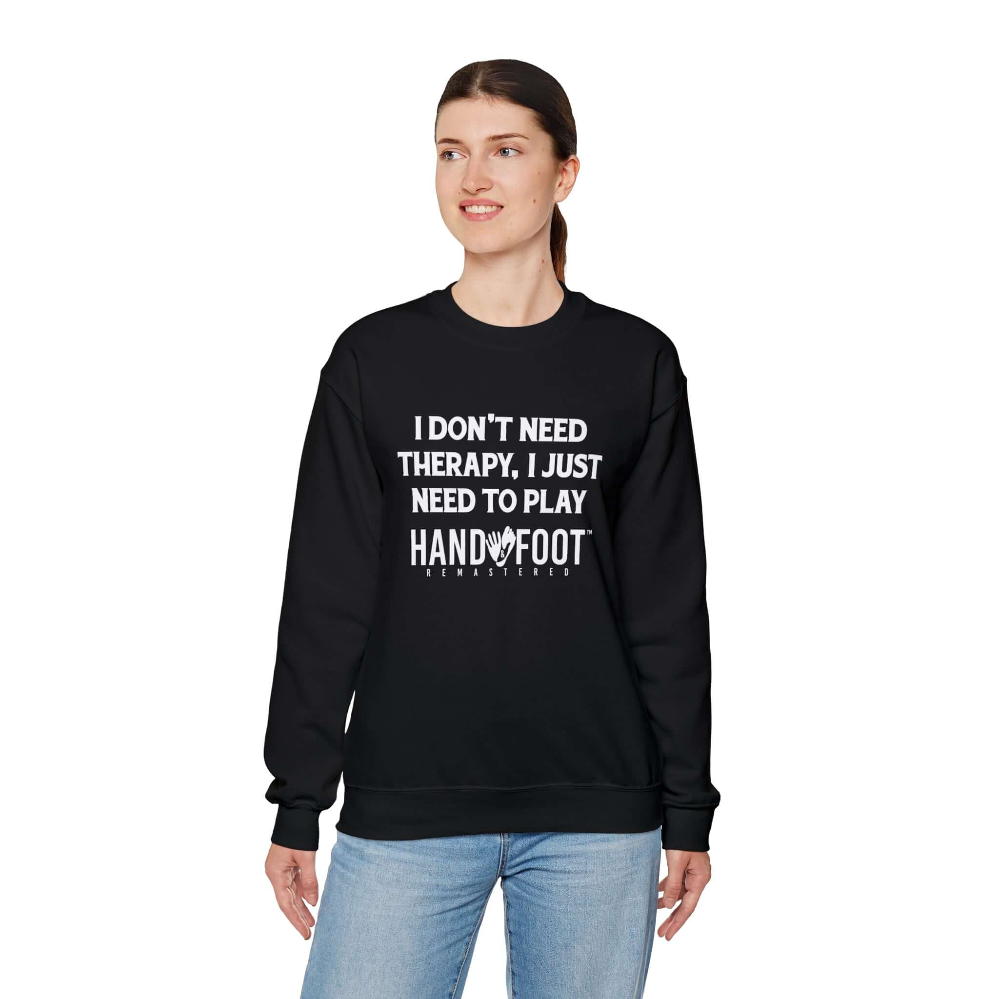 Woman wearing black Therapy Unisex Heavy Blend Crewneck Sweatshirt with Hand & Foot Remastered text, standing against white background.