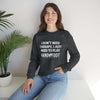 Woman wearing Therapy Unisex Heavy Blend Crewneck Sweatshirt with Hand & Foot Remastered slogan, sitting next to a plant.