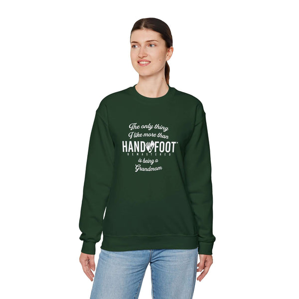 Model wearing a green 'Being a Grandmom' unisex heavy blend crewneck sweatshirt with white lettering.