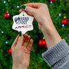 Hand holding Hand & Foot Addict ceramic ornament in front of Christmas tree; glossy star shape design with typography.
