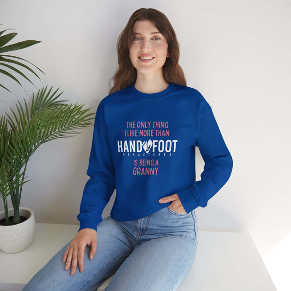 Woman wearing blue unisex crewneck sweatshirt with 'Being a Granny' text, sitting by plants, showcasing cozy style.