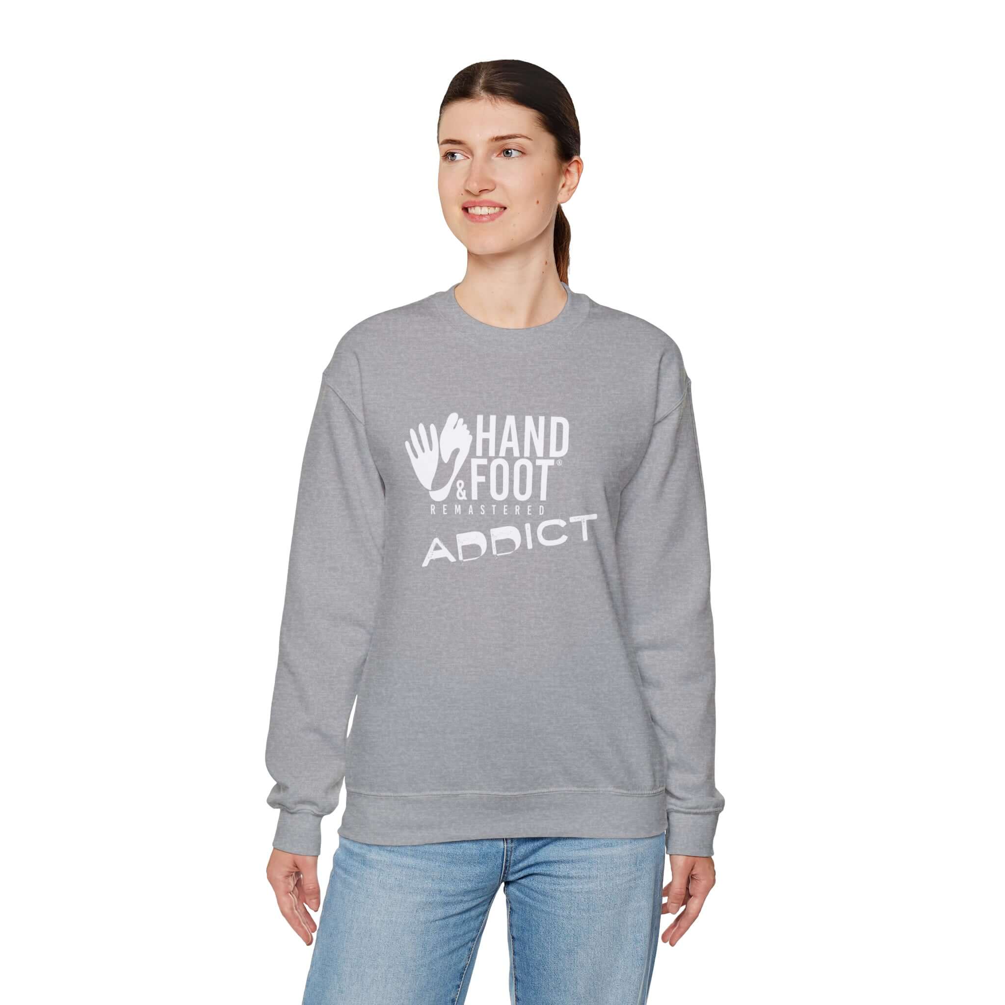 Unisex grey sweatshirt with Hand & Foot Addict design, worn by person in jeans, showcasing comfort and sustainable fashion.