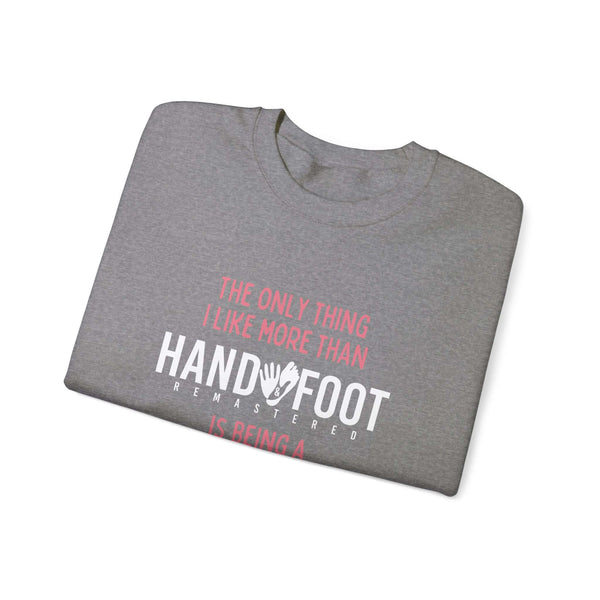 Folded grey sweatshirt with "The Only Thing I Like More Than Hand and Foot is Being a" printed in pink and white text.
