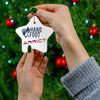 Person holding star-shaped Hand & Foot Addict ceramic ornament near Christmas tree.