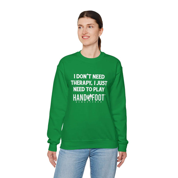 Person wearing a green Therapy Unisex Heavy Blend Crewneck Sweatshirt with 'I Don't Need Therapy, I Just Need to Play Hand & Foot' print.