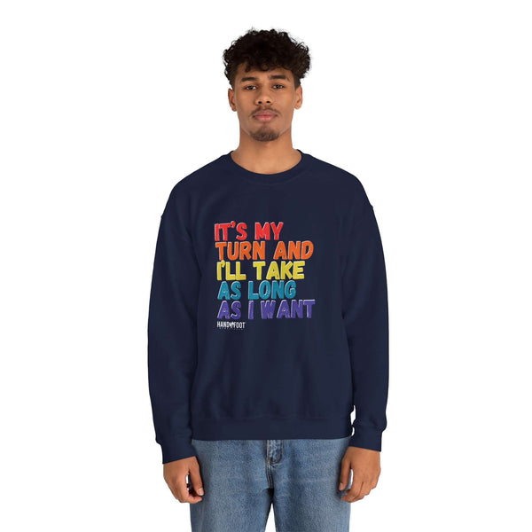 Model wearing 'It's My Turn' unisex heavy blend crewneck sweatshirt with colorful text design.