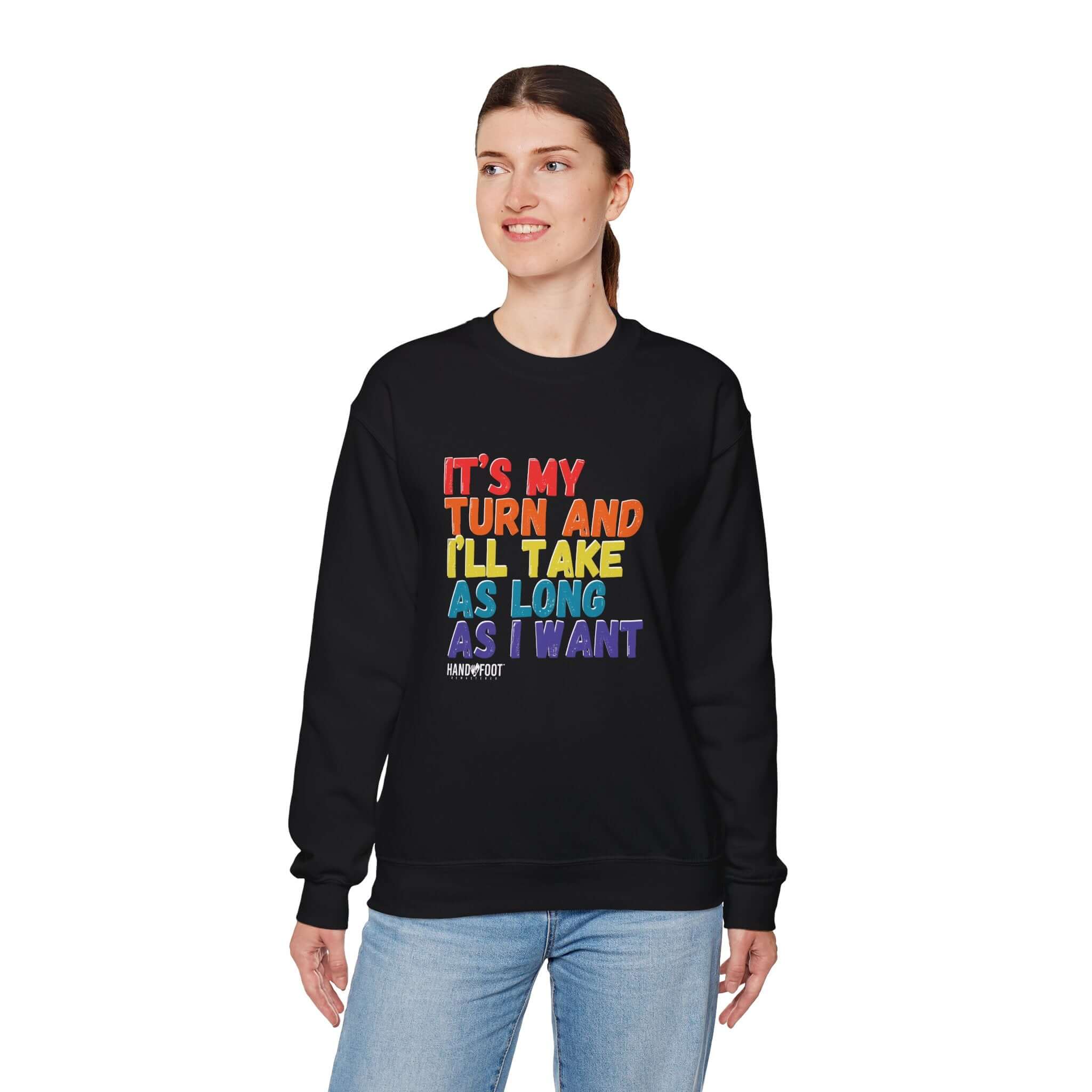 Person wearing 'It's My Turn' unisex crewneck sweatshirt in black with colorful text.