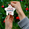 Person holding star-shaped Being a Grandpa ceramic ornament with Christmas tree in background.