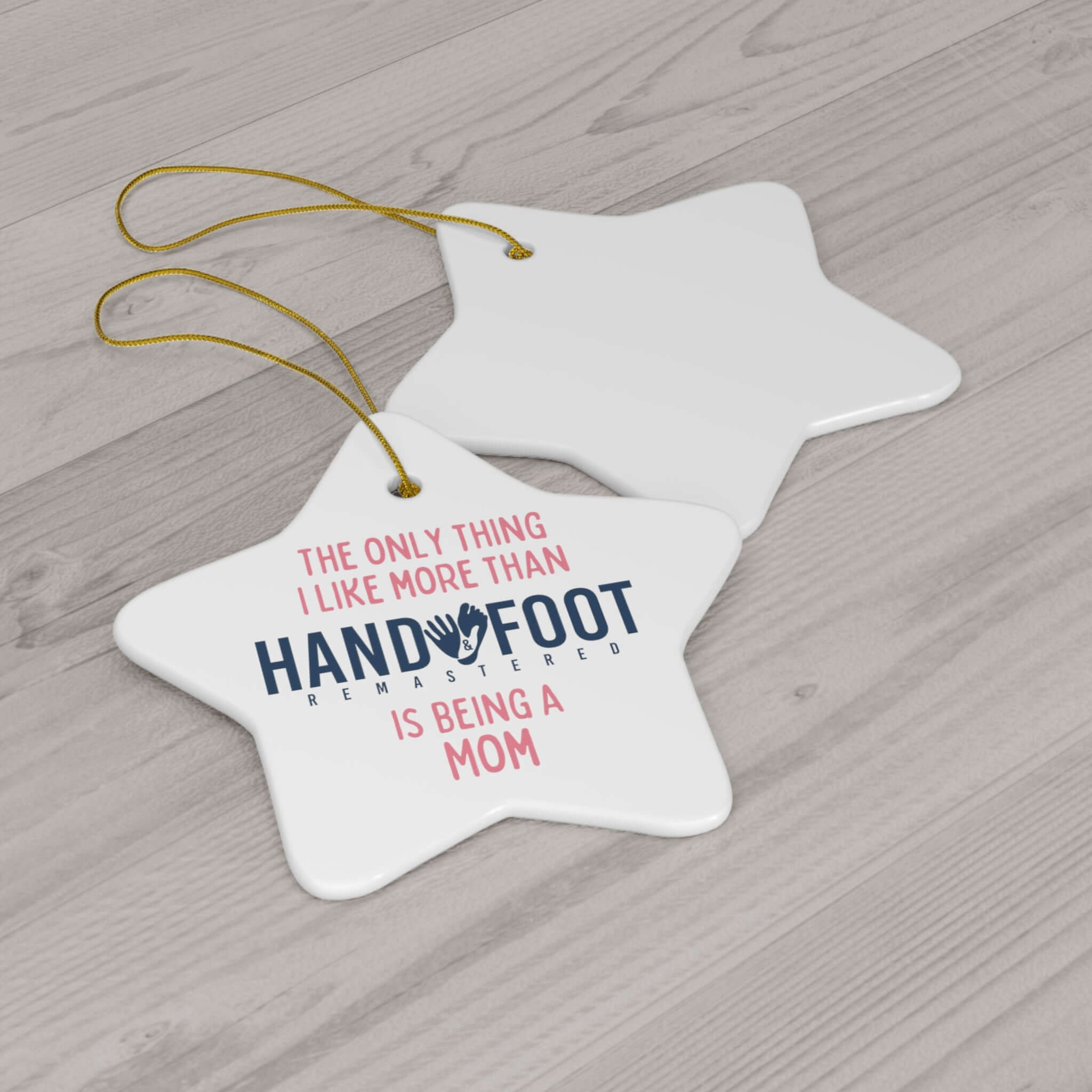 Star-shaped ceramic ornament with the text 'The only thing I like more than Hand Foot Remastered is being a mom' and a gold-toned hanging ribbon.