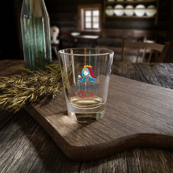 Hand & Foot Queen Shot Glass on wooden table in cozy setting, perfect for parties and celebrations.